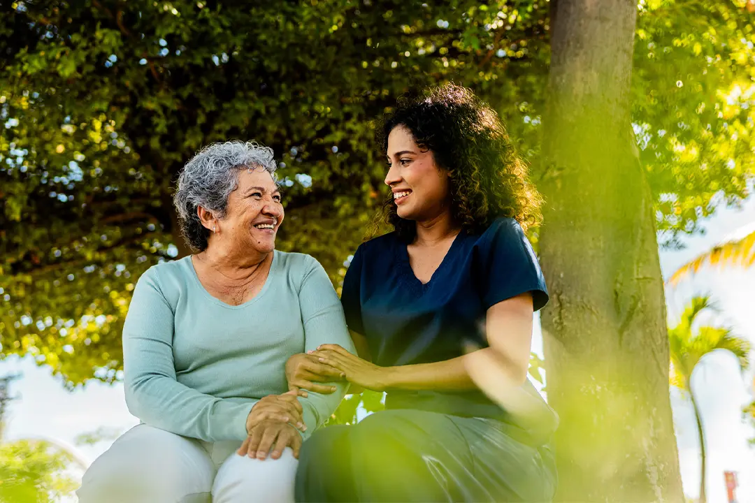 A care team member supporting an assisted-living resident with a walking aid.